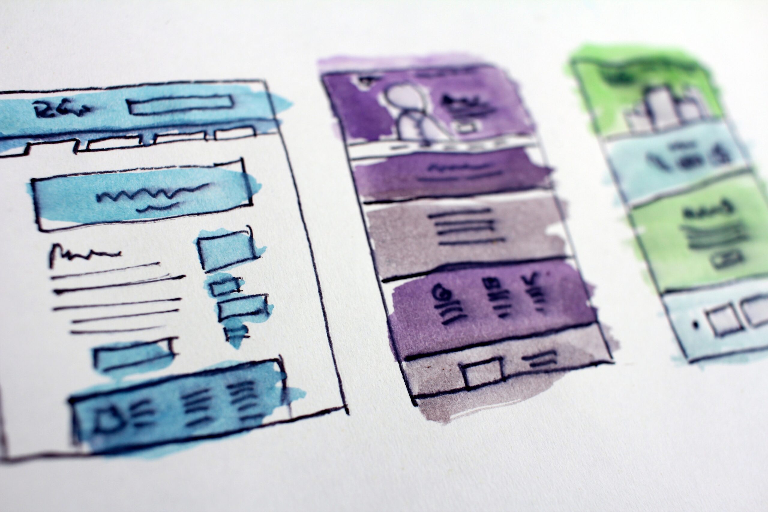A photo of a drawing. The drawing is of a row of three waterclour web pages. From left to right they are: blue, purple and green.