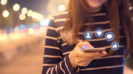 Woman hands using mobile smartphone on the street with icon social media and social network.