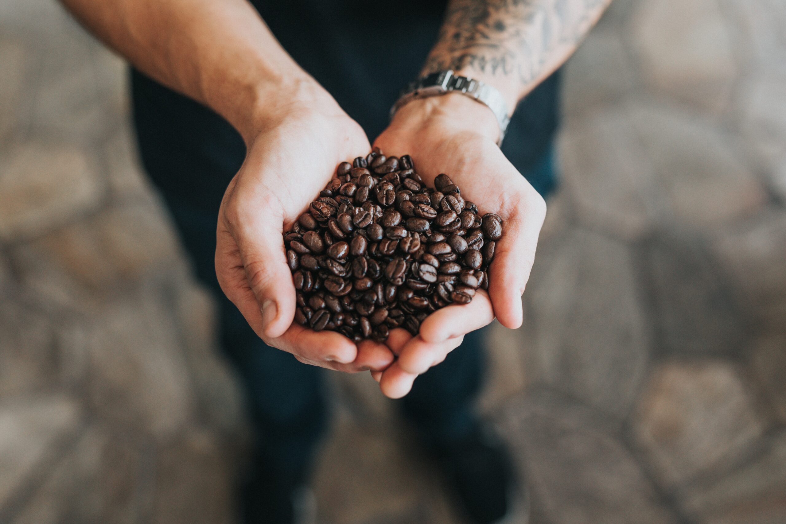 A man holding his two hands out. They are full of coffee beans.
