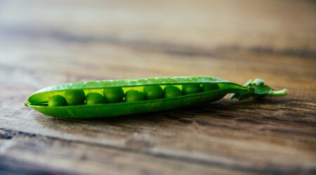 a pod of peas on a wooden table.