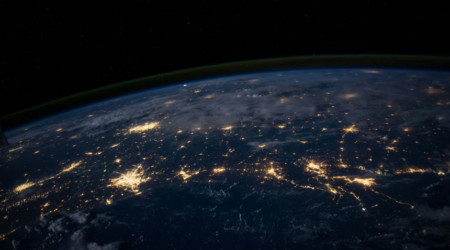 satellite view of earth at night with cities lighting it up